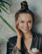 Beautiful young woman applying moisturizer on her face
